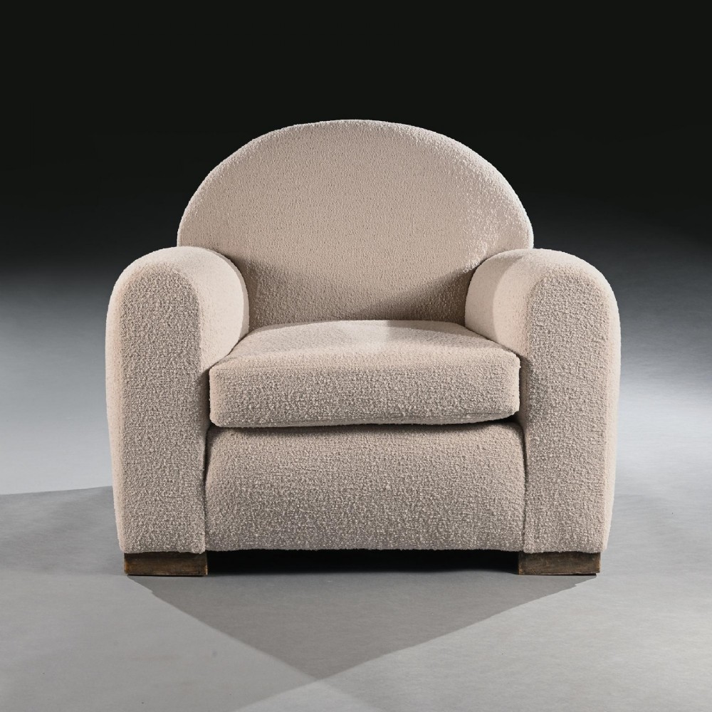 A pair of mid-twentieth-century French club armchairs upholstered in cream boucle fabric with rounded backrests and low wooden block feet. View V