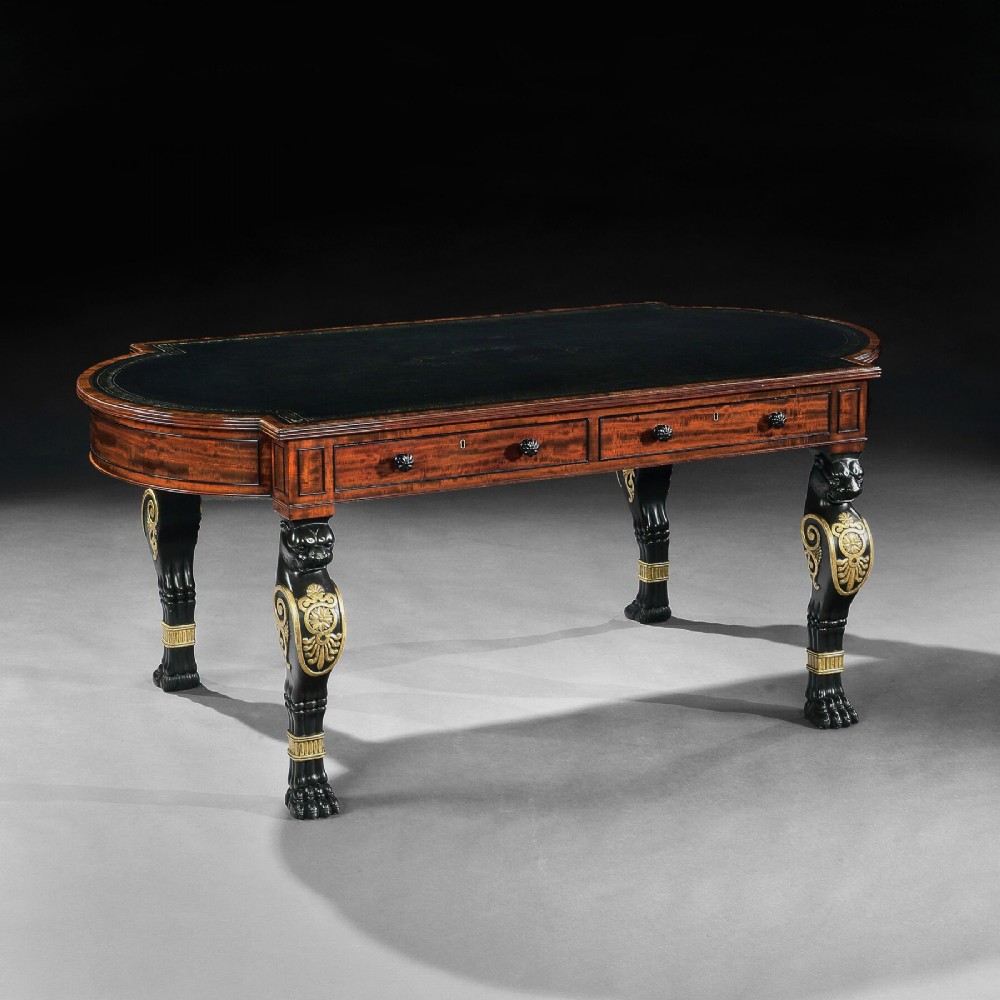 A Regency mahogany partners writing table with a dark leather inset top, frieze drawers, and ebonised lion monopodia legs adorned with gilt highlights.