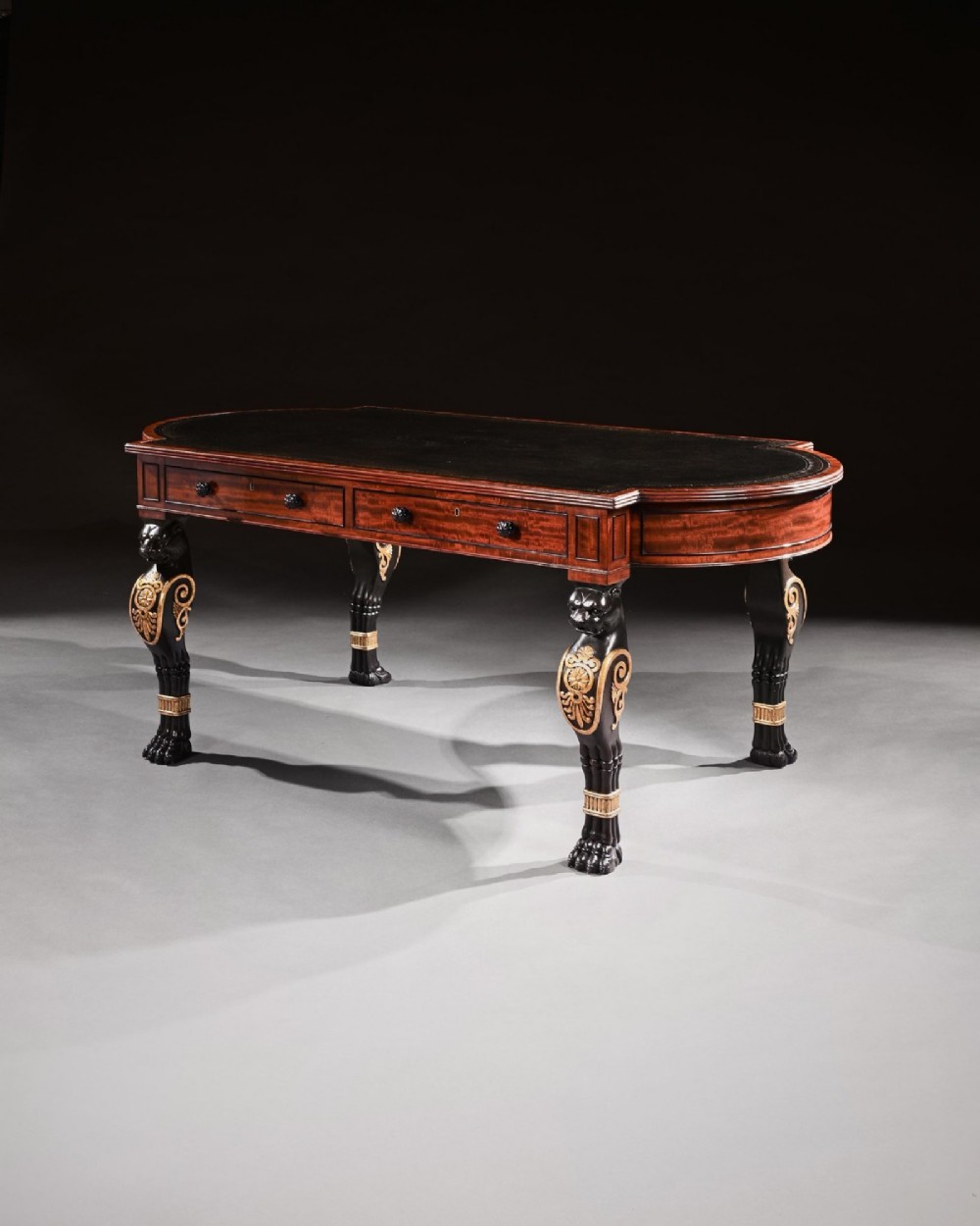 A Regency mahogany partners writing table with a dark leather inset top, frieze drawers, and ebonised lion monopodia legs adorned with gilt highlights. View II