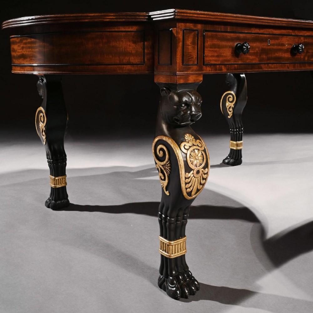 A Regency mahogany partners writing table with a dark leather inset top, frieze drawers, and ebonised lion monopodia legs adorned with gilt highlights. View V