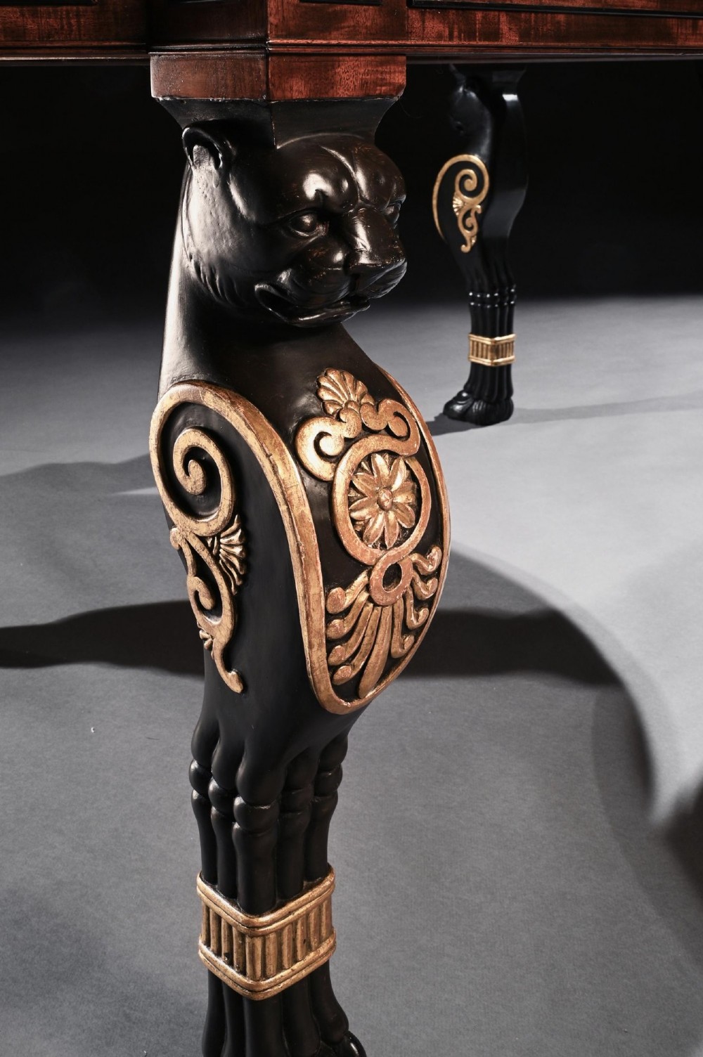 A Regency mahogany partners writing table with a dark leather inset top, frieze drawers, and ebonised lion monopodia legs adorned with gilt highlights. View VII