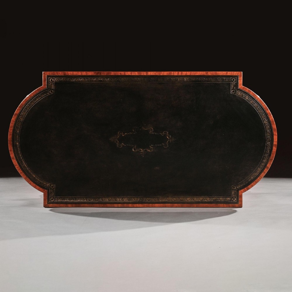 A Regency mahogany partners writing table with a dark leather inset top, frieze drawers, and ebonised lion monopodia legs adorned with gilt highlights. View X