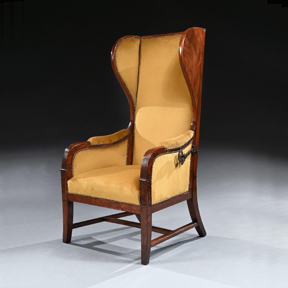 A French Empire style reclining wing back armchair with dark mahogany framing, brass stud detailing, and yellow velvet upholstery.