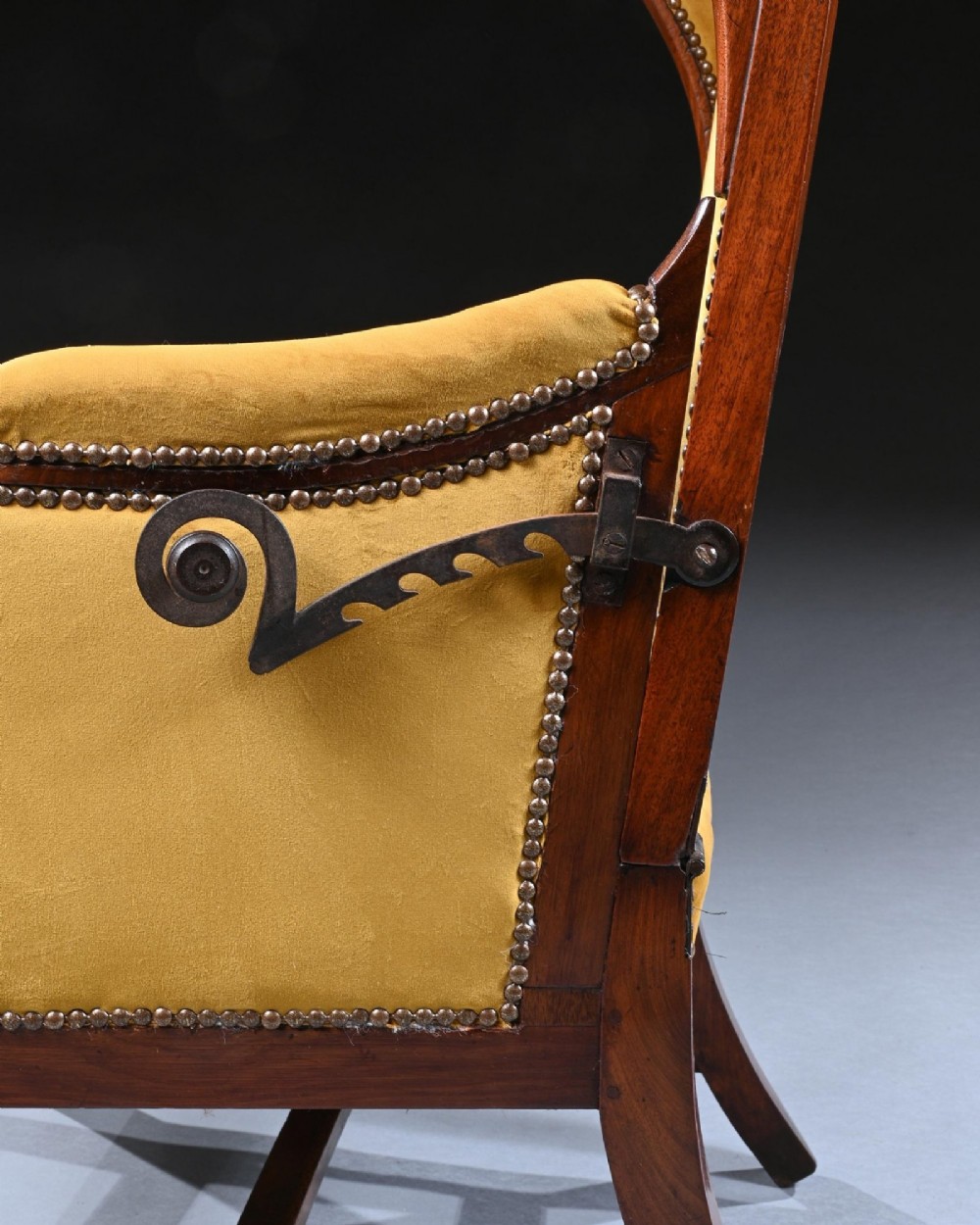 A French Empire style reclining wing back armchair with dark mahogany framing, brass stud detailing, and yellow velvet upholstery. View IV