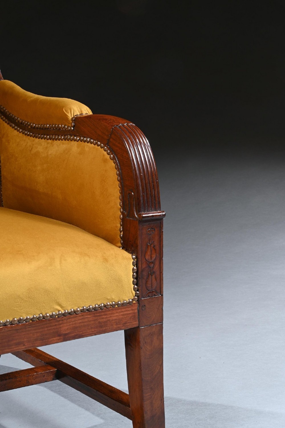 A French Empire style reclining wing back armchair with dark mahogany framing, brass stud detailing, and yellow velvet upholstery. View V