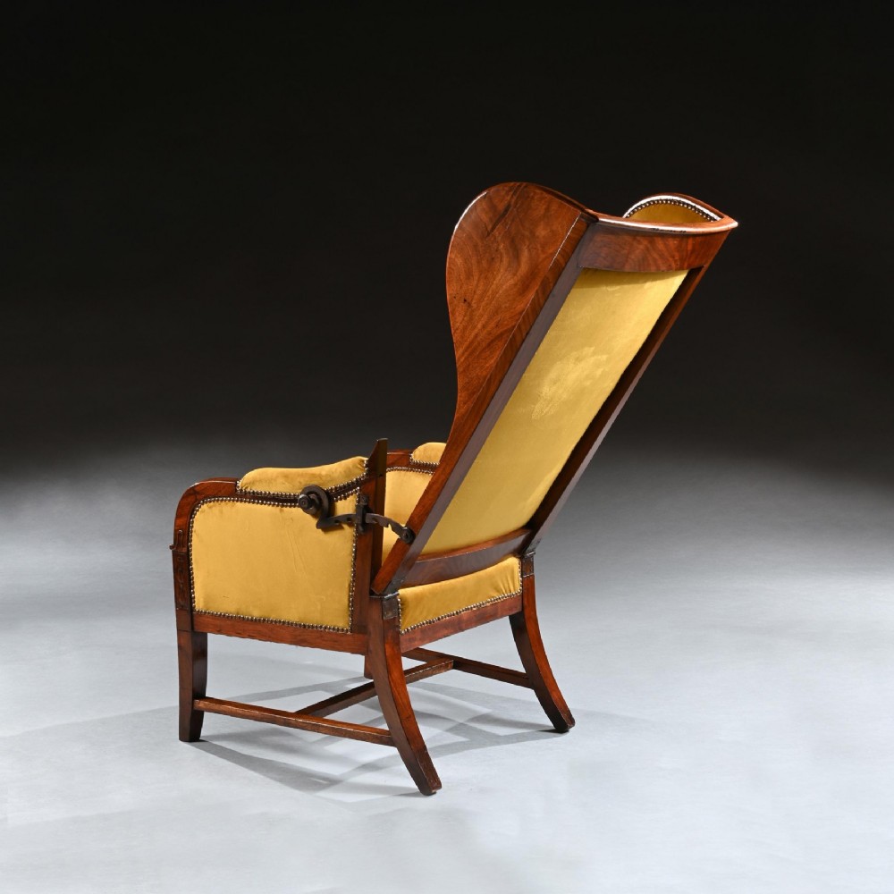 A French Empire style reclining wing back armchair with dark mahogany framing, brass stud detailing, and yellow velvet upholstery. View VI