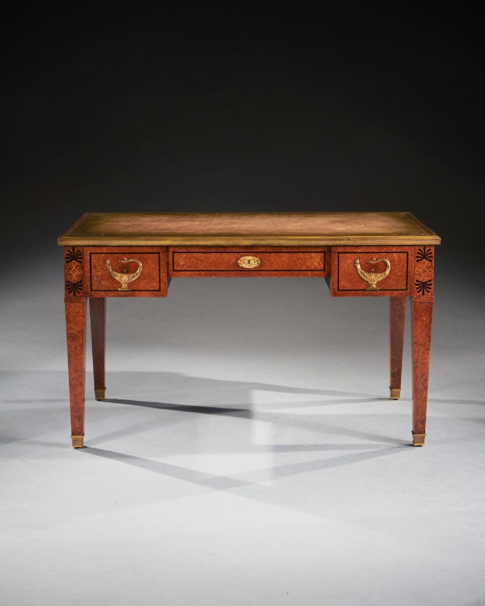A French Neoclassical style amboyna writing table featuring gilt bronze mounts, three front drawers, and tapered square legs. View III
