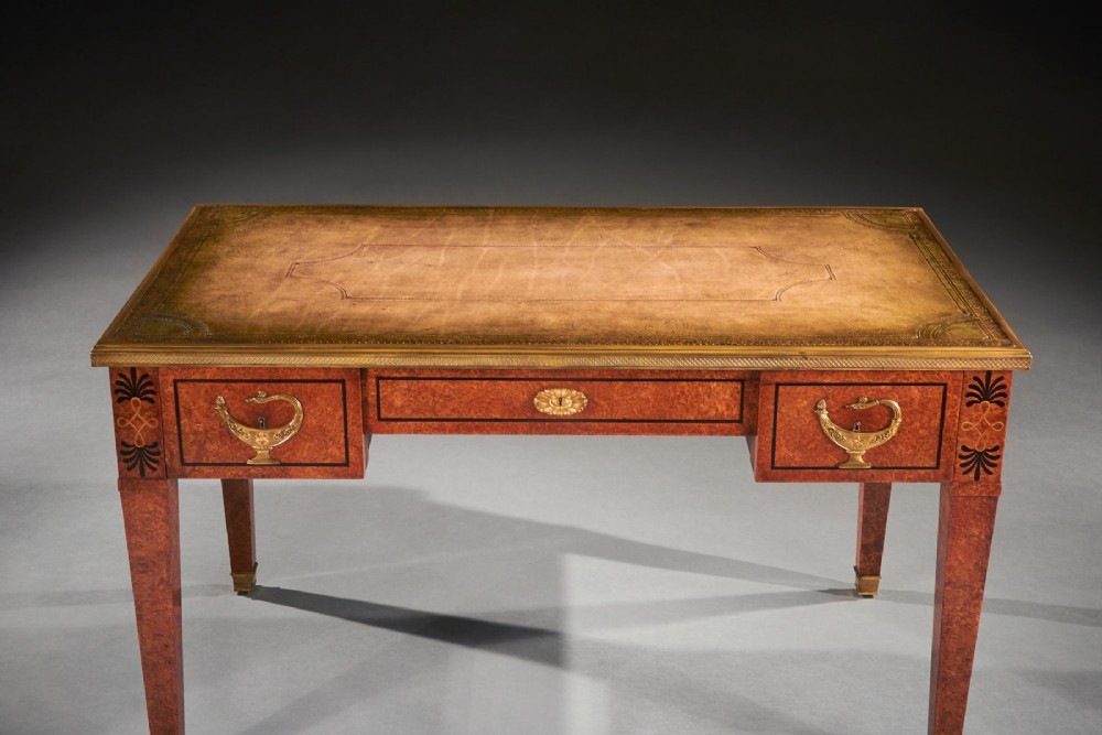 A French Neoclassical style amboyna writing table featuring gilt bronze mounts, three front drawers, and tapered square legs. View IV