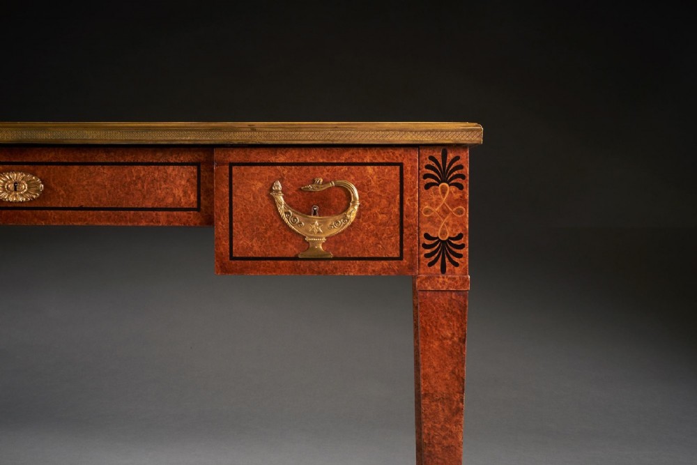 A French Neoclassical style amboyna writing table featuring gilt bronze mounts, three front drawers, and tapered square legs. View V