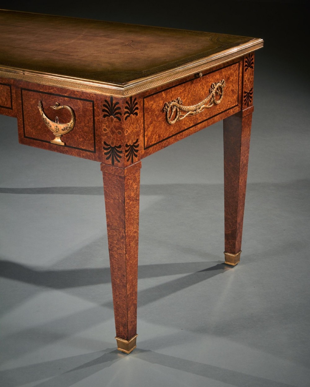 A French Neoclassical style amboyna writing table featuring gilt bronze mounts, three front drawers, and tapered square legs. View VI