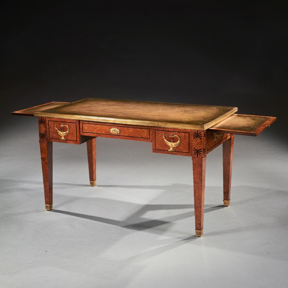 A French Neoclassical style amboyna writing table featuring gilt bronze mounts, three front drawers, and tapered square legs. View VIII
