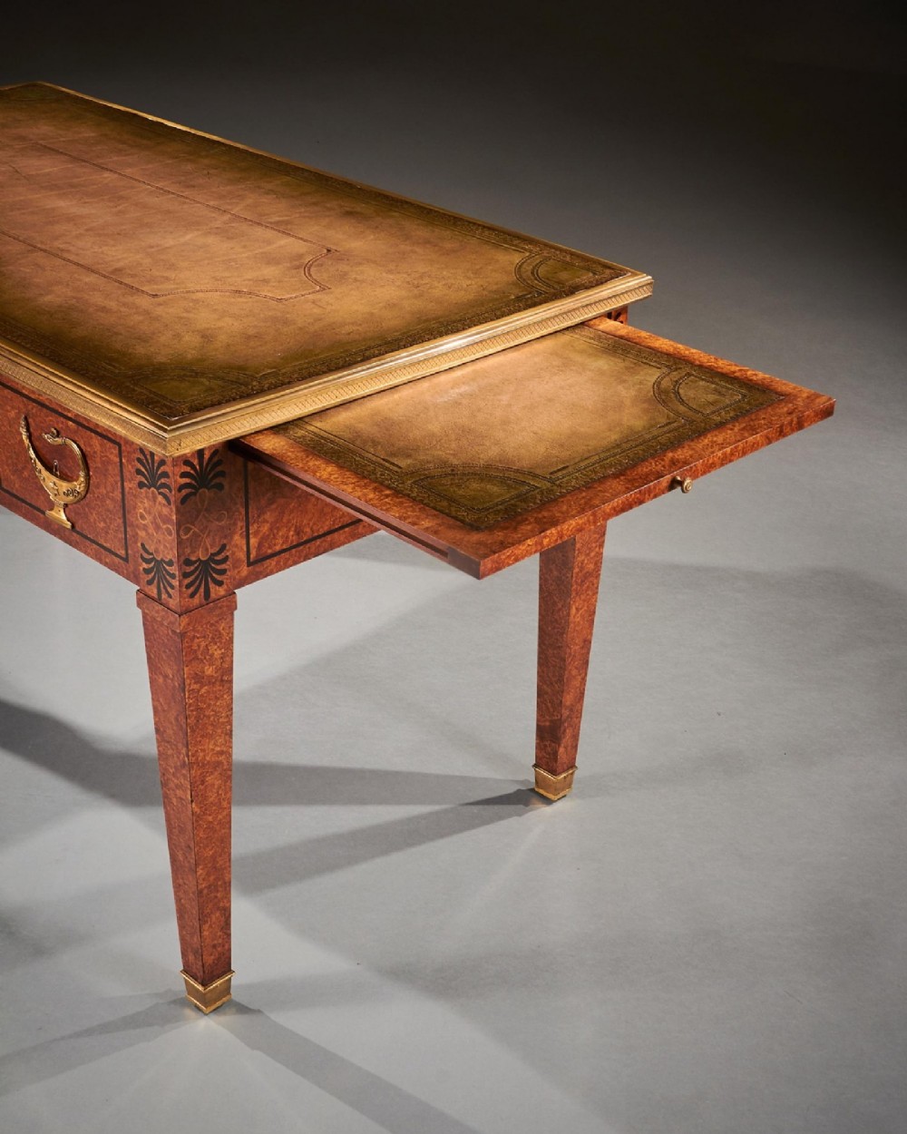 A French Neoclassical style amboyna writing table featuring gilt bronze mounts, three front drawers, and tapered square legs. View IX