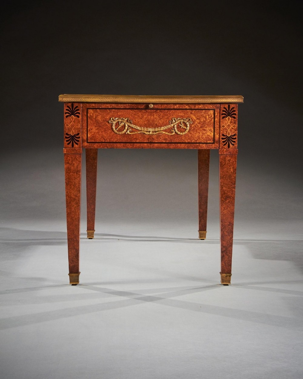 A French Neoclassical style amboyna writing table featuring gilt bronze mounts, three front drawers, and tapered square legs. View X