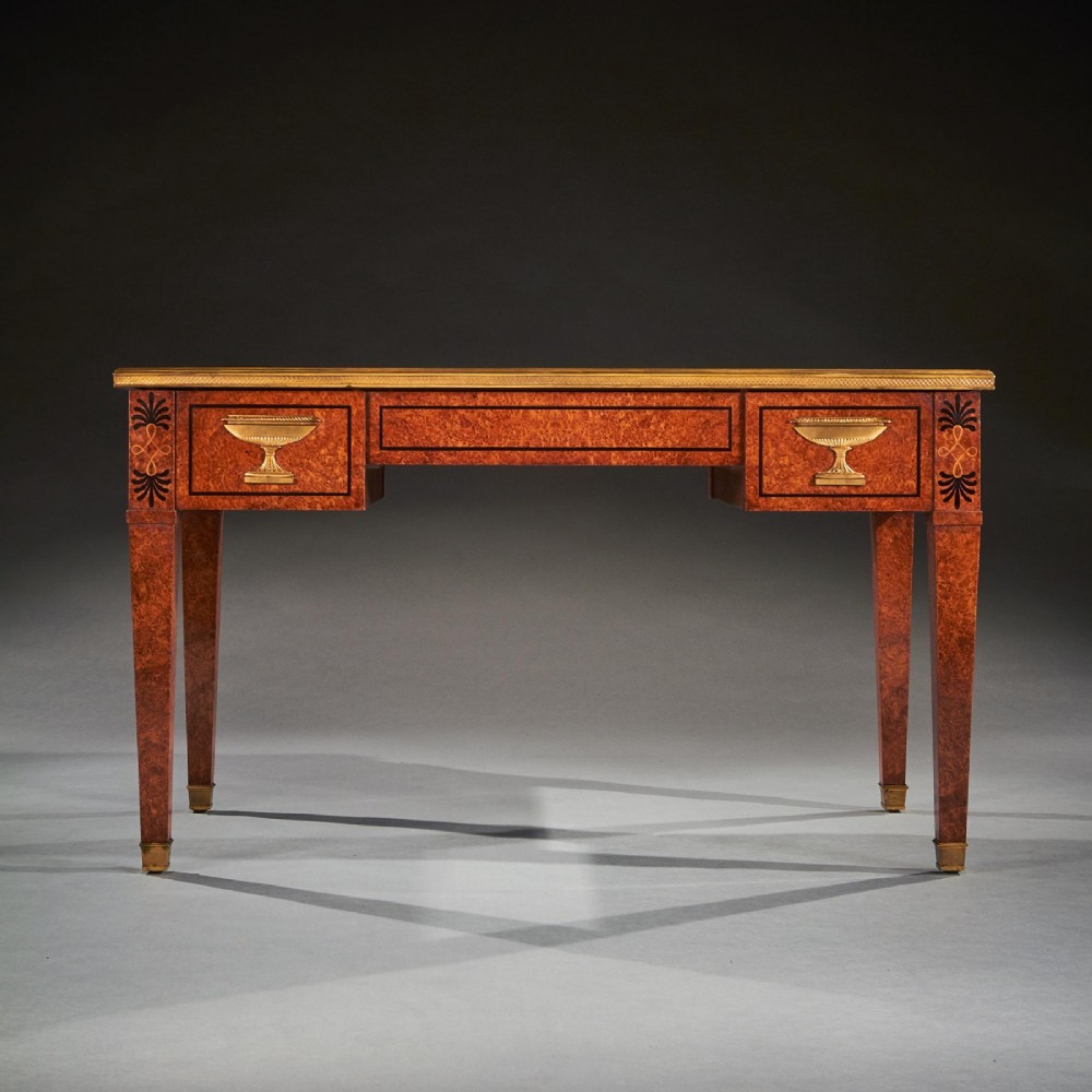 A French Neoclassical style amboyna writing table featuring gilt bronze mounts, three front drawers, and tapered square legs. View XI