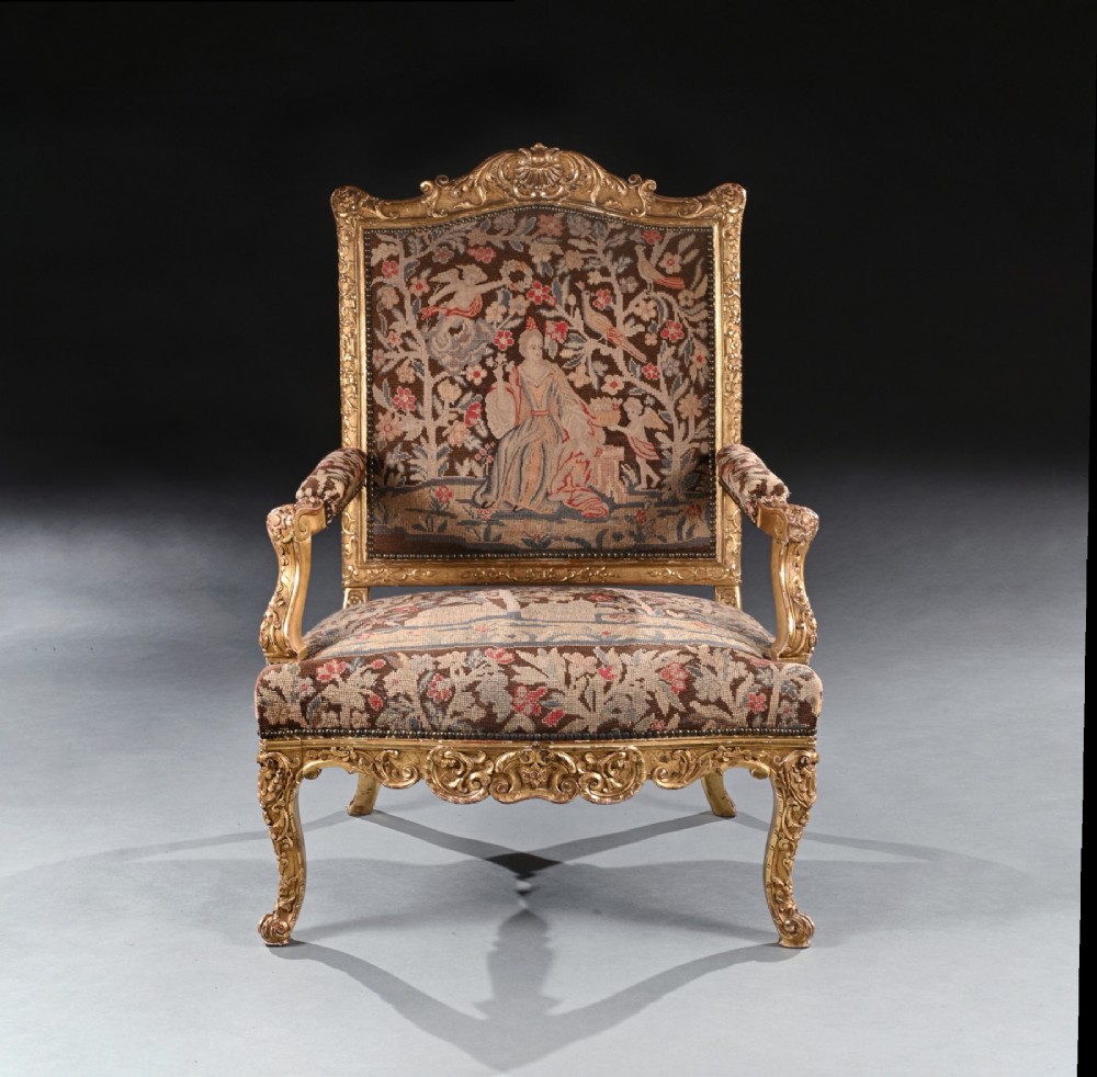 An 18th-century French Regence giltwood armchair featuring ornate shell carving, cabriole legs, and tapestry upholstery depicting figures and floral motifs. View II