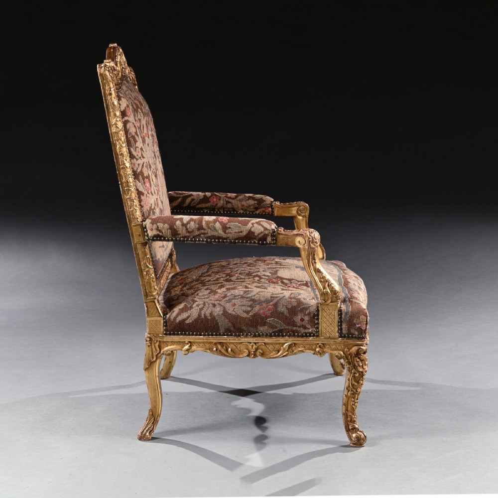 An 18th-century French Regence giltwood armchair featuring ornate shell carving, cabriole legs, and tapestry upholstery depicting figures and floral motifs. View III