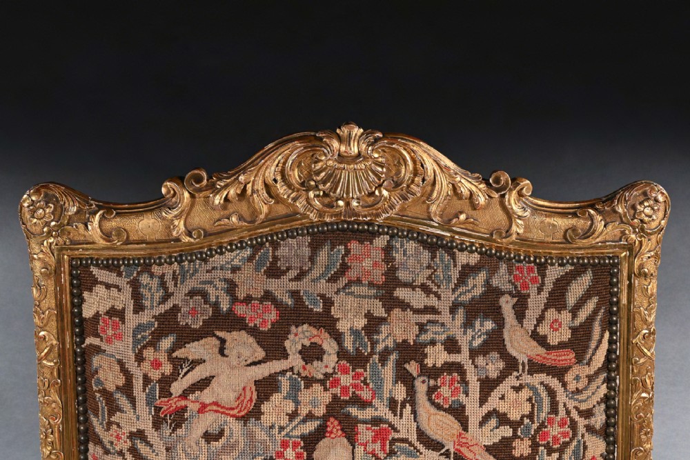 An 18th-century French Regence giltwood armchair featuring ornate shell carving, cabriole legs, and tapestry upholstery depicting figures and floral motifs. View IV