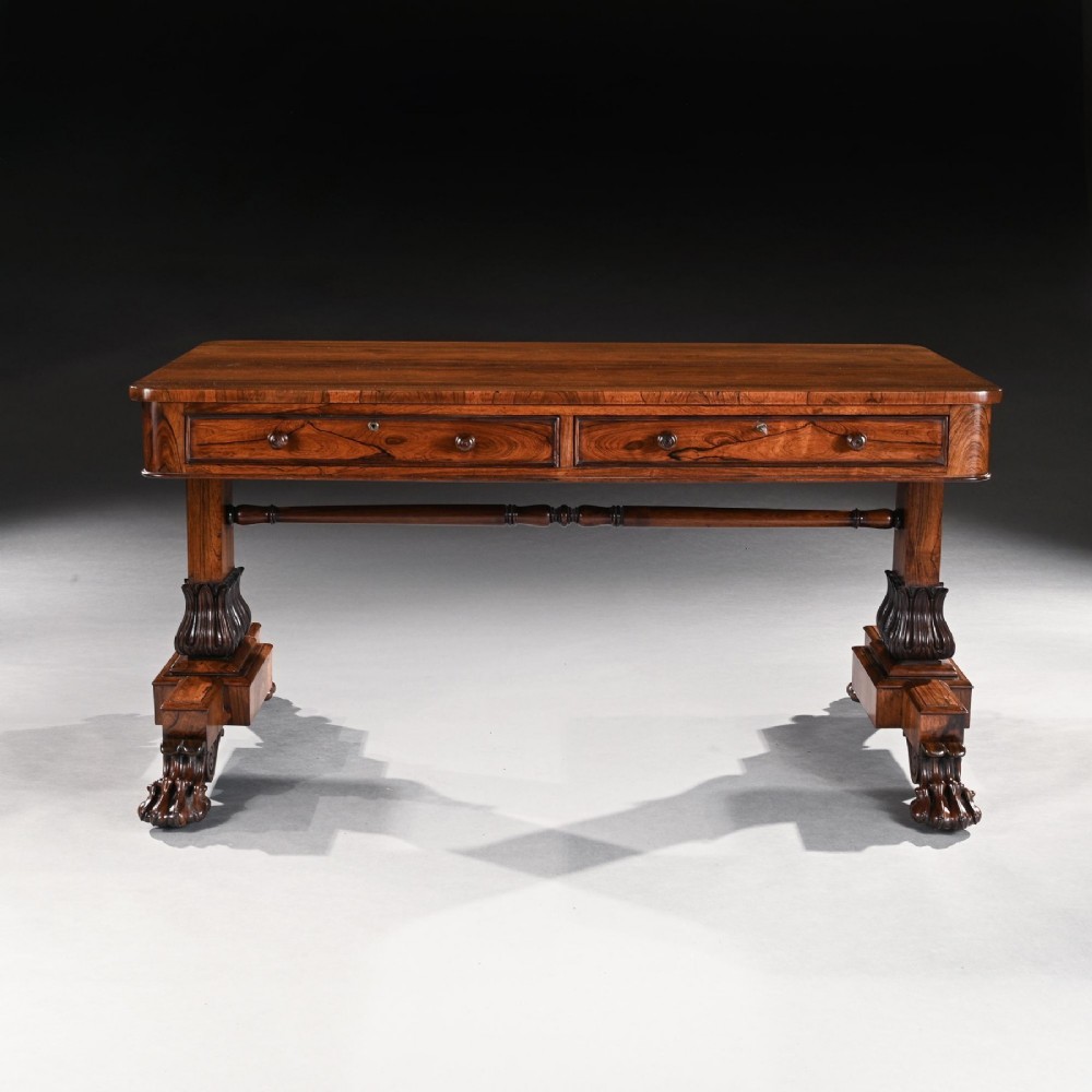 A George IV period rosewood library table featuring two frieze drawers, a turned central stretcher, and pedestal supports ending in carved lions paw feet. View II
