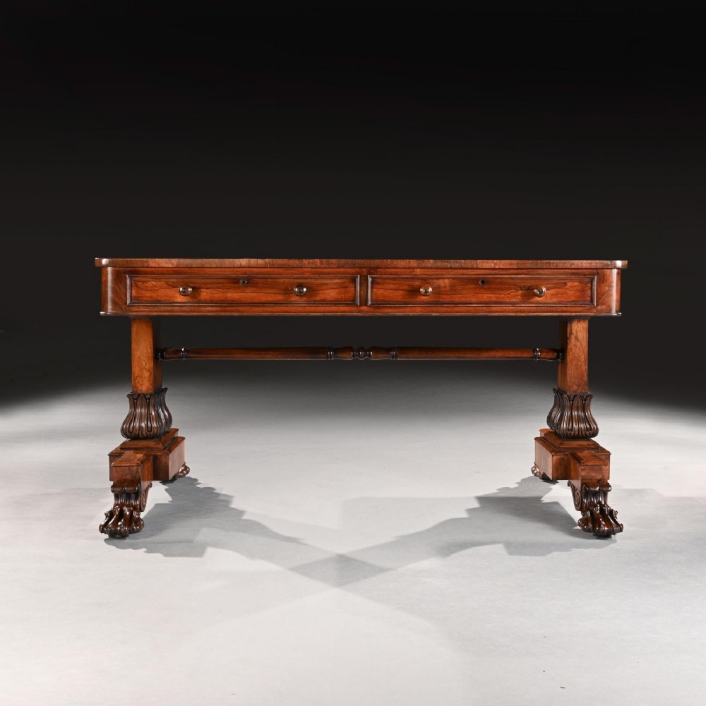 A George IV period rosewood library table featuring two frieze drawers, a turned central stretcher, and pedestal supports ending in carved lions paw feet. View V