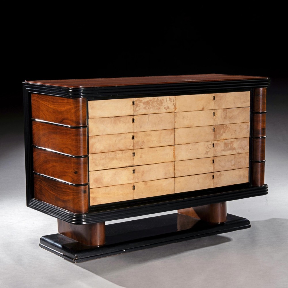 An Art Deco palisander commode featuring twelve parchment-covered drawer fronts, ebonised side trim, curved timber flanks, and a stepped plinth base. View III