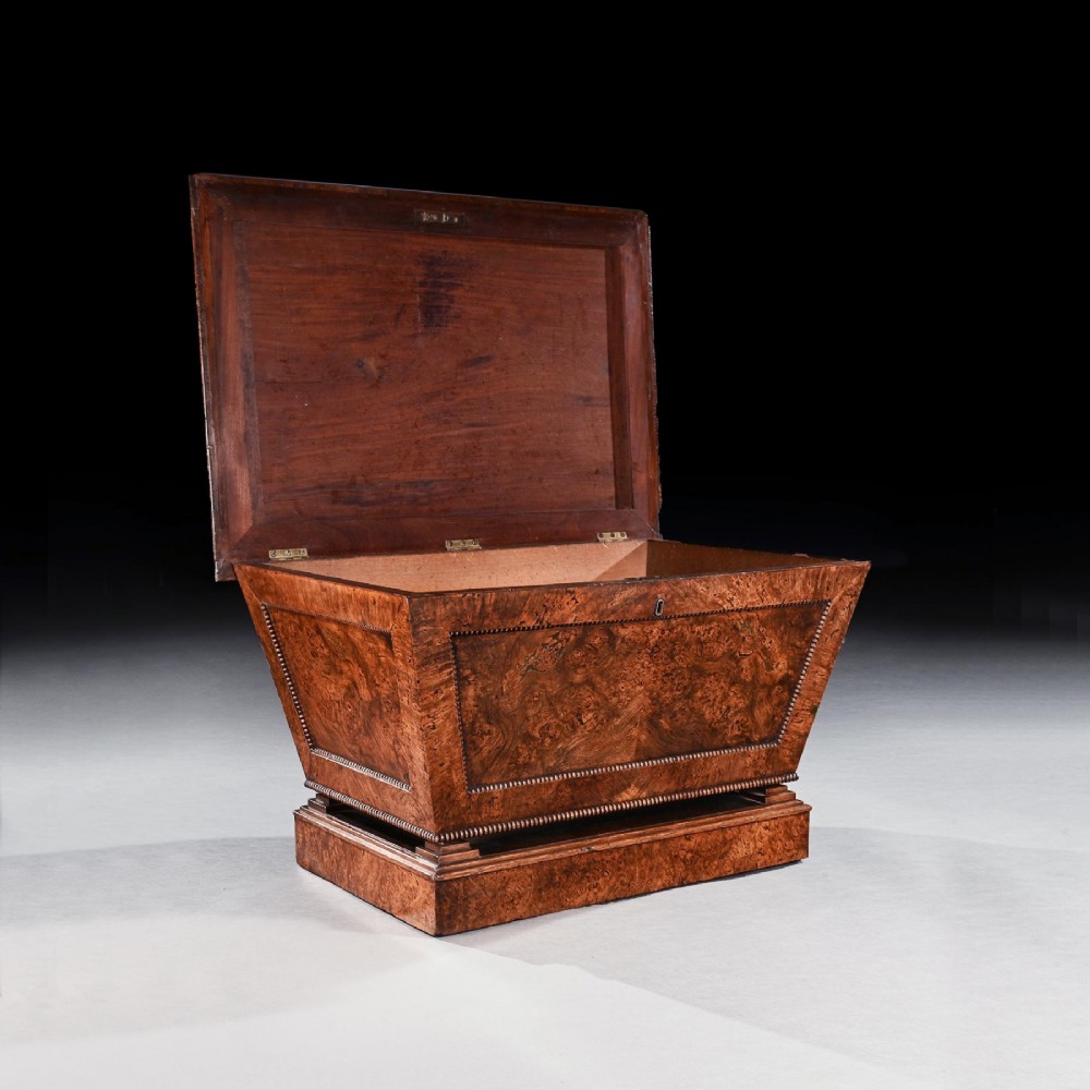 A George IV sarcophagus-shaped cellarette crafted from figured pollard oak with a stepped lid and beaded moulding on a plinth base. View II