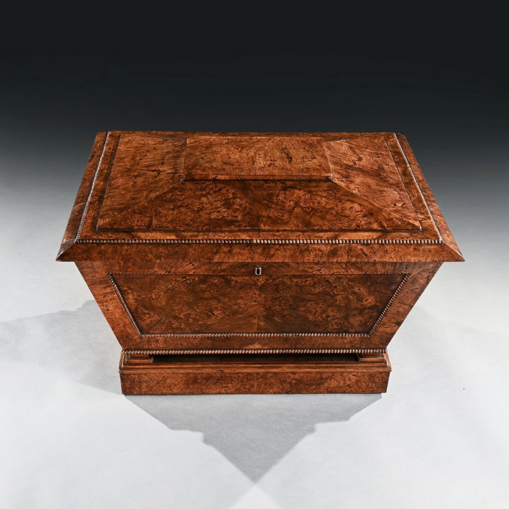 A George IV sarcophagus-shaped cellarette crafted from figured pollard oak with a stepped lid and beaded moulding on a plinth base. View IV