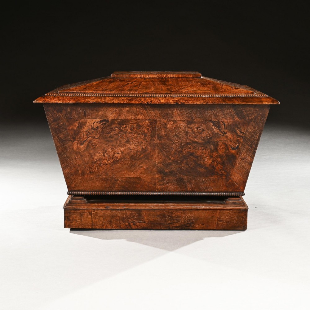 A George IV sarcophagus-shaped cellarette crafted from figured pollard oak with a stepped lid and beaded moulding on a plinth base. View VI