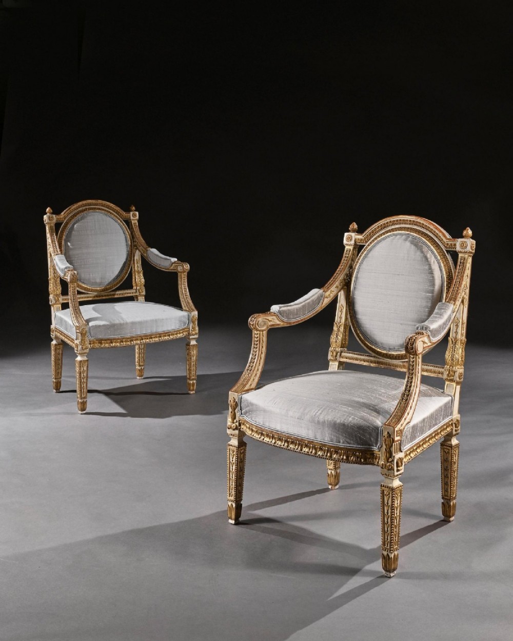 A pair of 19th-century Italian Neoclassical armchairs featuring cream painted and gilt carved frames, oval backrests, and light grey silk upholstery. View II