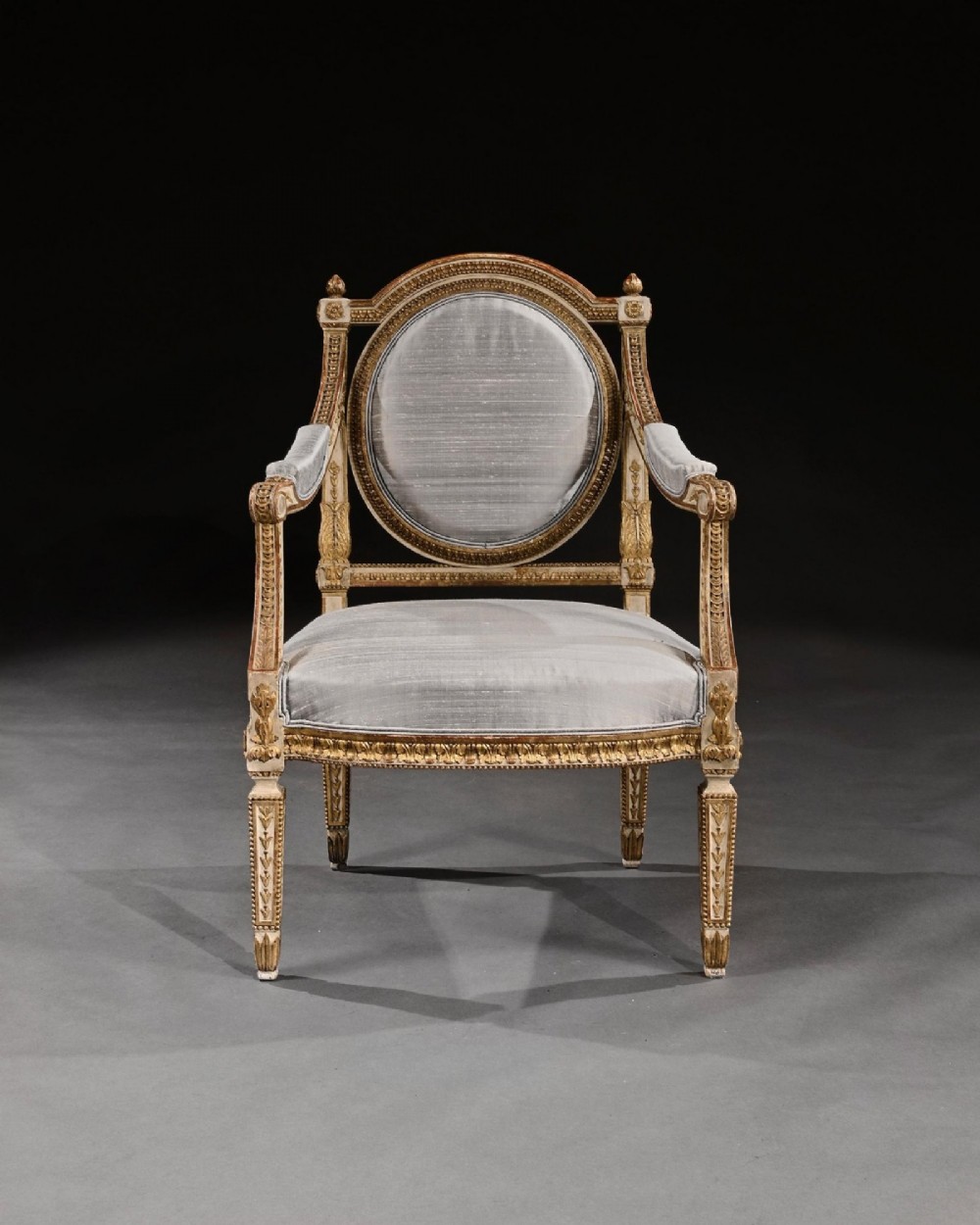 A pair of 19th-century Italian Neoclassical armchairs featuring cream painted and gilt carved frames, oval backrests, and light grey silk upholstery. View III