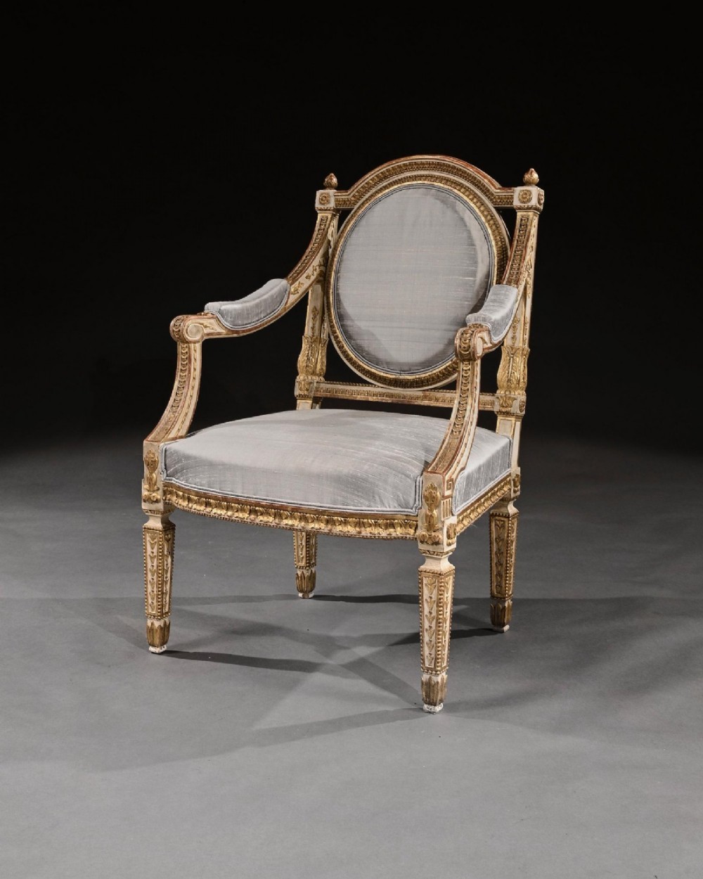 A pair of 19th-century Italian Neoclassical armchairs featuring cream painted and gilt carved frames, oval backrests, and light grey silk upholstery. View IV