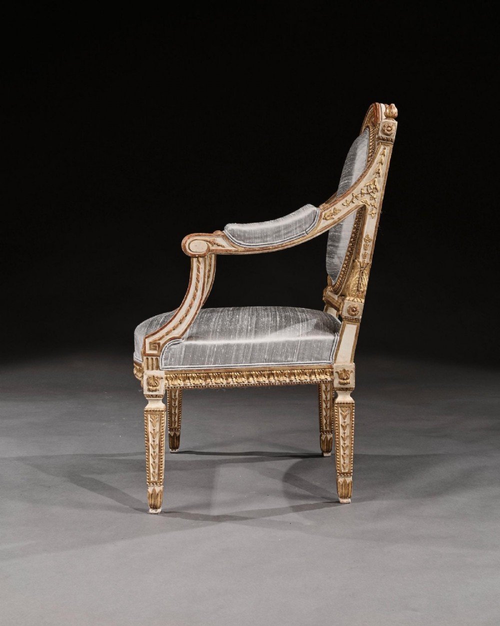 A pair of 19th-century Italian Neoclassical armchairs featuring cream painted and gilt carved frames, oval backrests, and light grey silk upholstery. View V