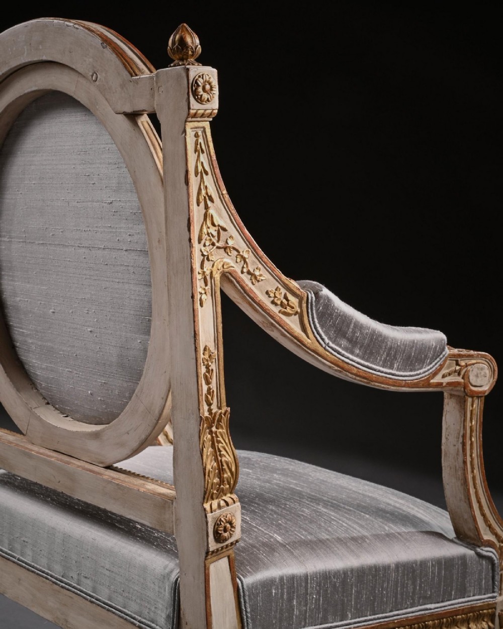 A pair of 19th-century Italian Neoclassical armchairs featuring cream painted and gilt carved frames, oval backrests, and light grey silk upholstery. View IX