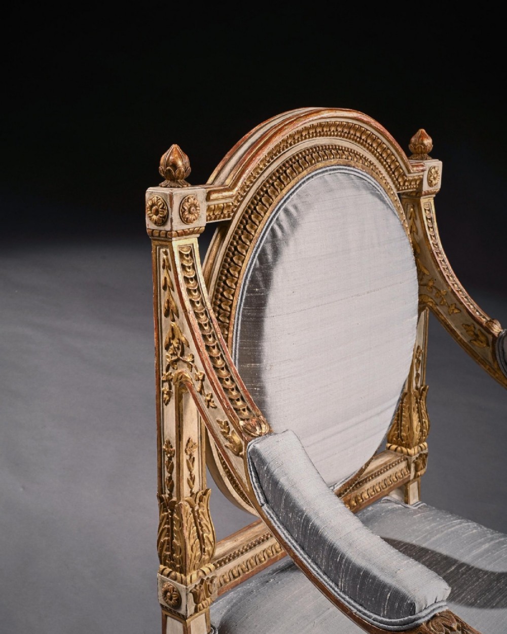 A pair of 19th-century Italian Neoclassical armchairs featuring cream painted and gilt carved frames, oval backrests, and light grey silk upholstery. View XI