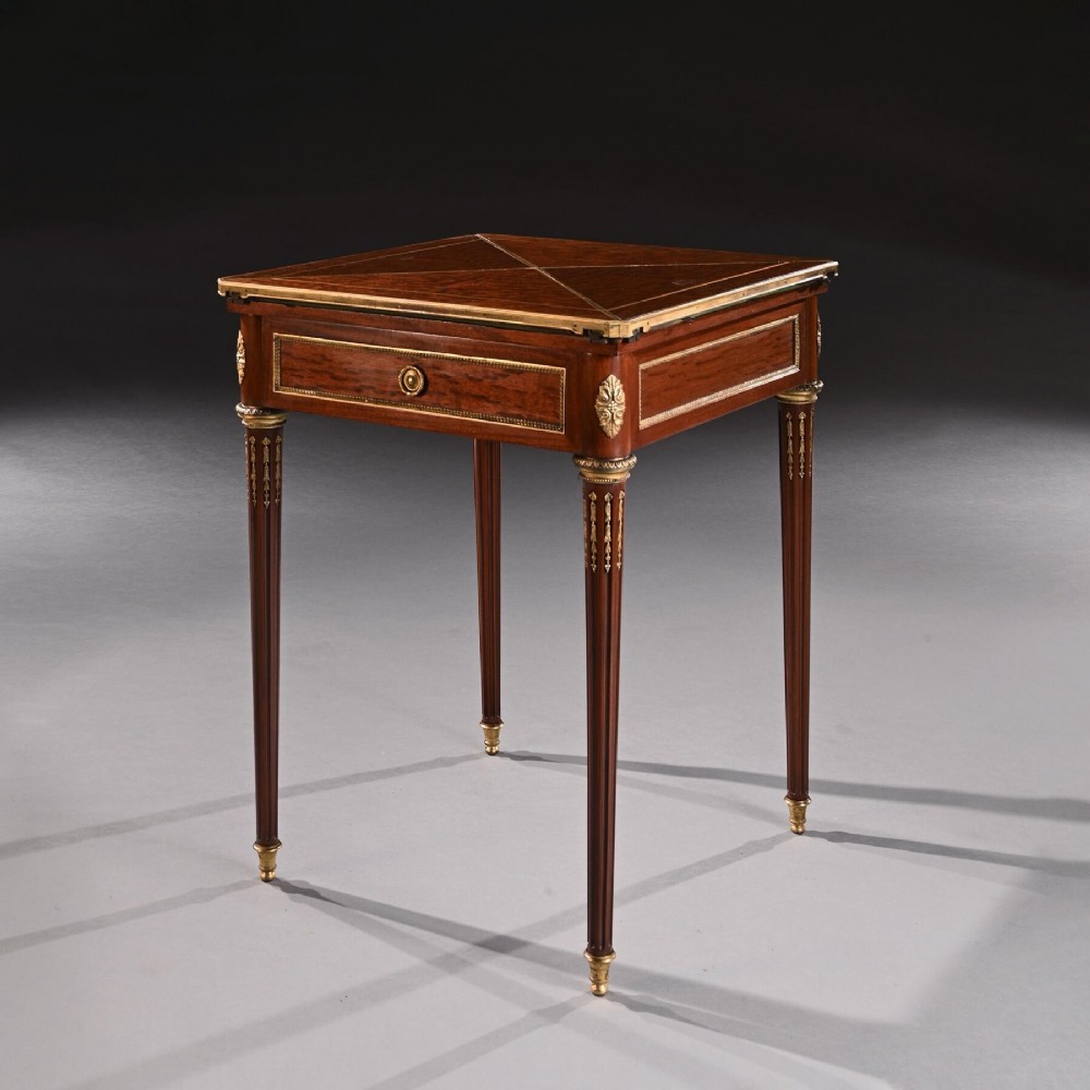 A square mahogany envelope card table with gilt bronze mounts, fluted tapered legs, and four triangular folding top flaps.