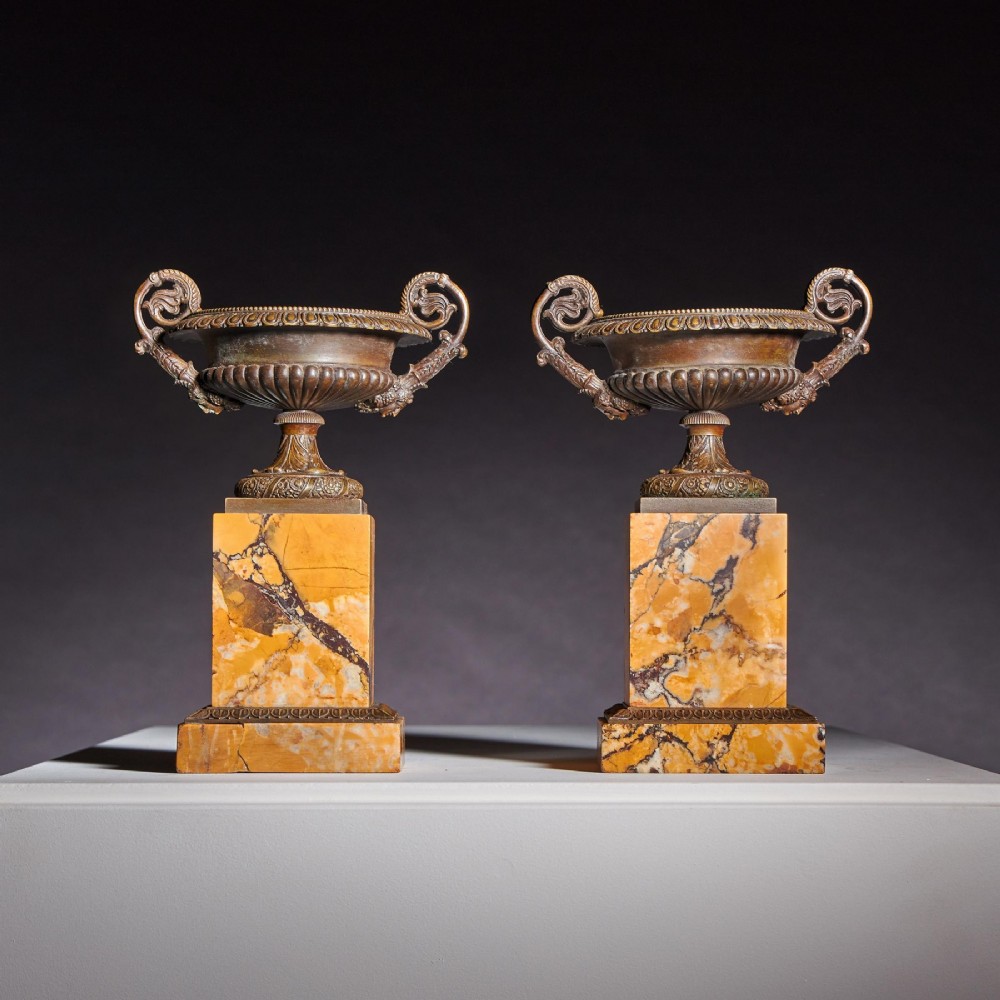A pair of early nineteenth-century French patinated bronze tazzas with ornate scroll handles mounted on square veined yellow marble plinths. View II