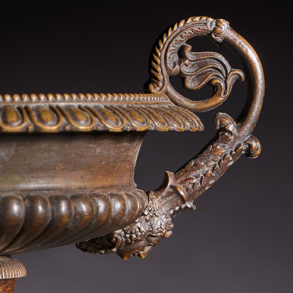 A pair of early nineteenth-century French patinated bronze tazzas with ornate scroll handles mounted on square veined yellow marble plinths. View IX