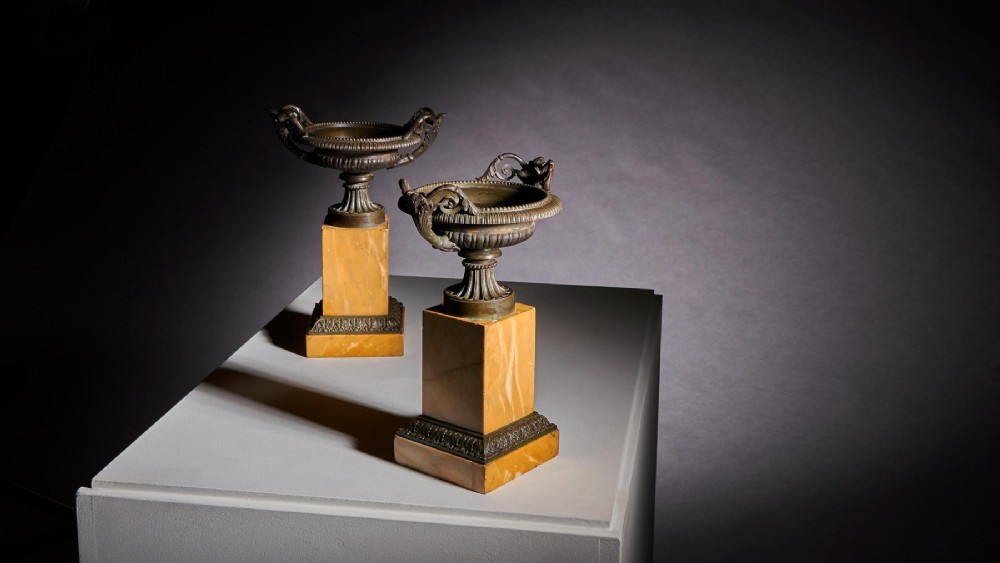 A pair of early 19th-century French Grand Tour bronze tazzas featuring fluted rims and scrolled handles set upon tall yellow Siena marble pedestal bases. View VII
