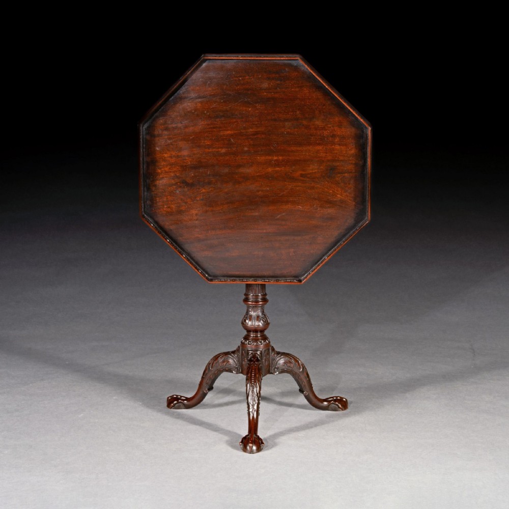 A George III dark mahogany octagonal tripod table featuring a pierced fretwork gallery top, fluted column, and carved legs with claw-and-ball feet. View II