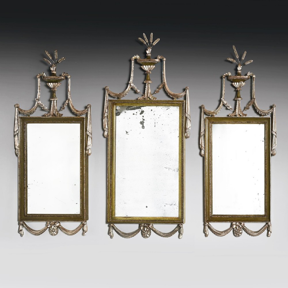 A set of three 19th-century Neoclassical wall mirrors featuring green painted and silvered frames topped with carved urn finials and drapery swags.