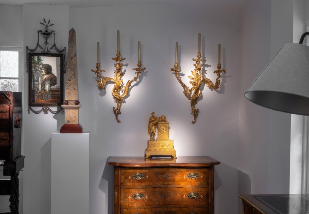 A set of three 19th-century Neoclassical wall mirrors featuring green painted and silvered frames topped with carved urn finials and drapery swags. View VI