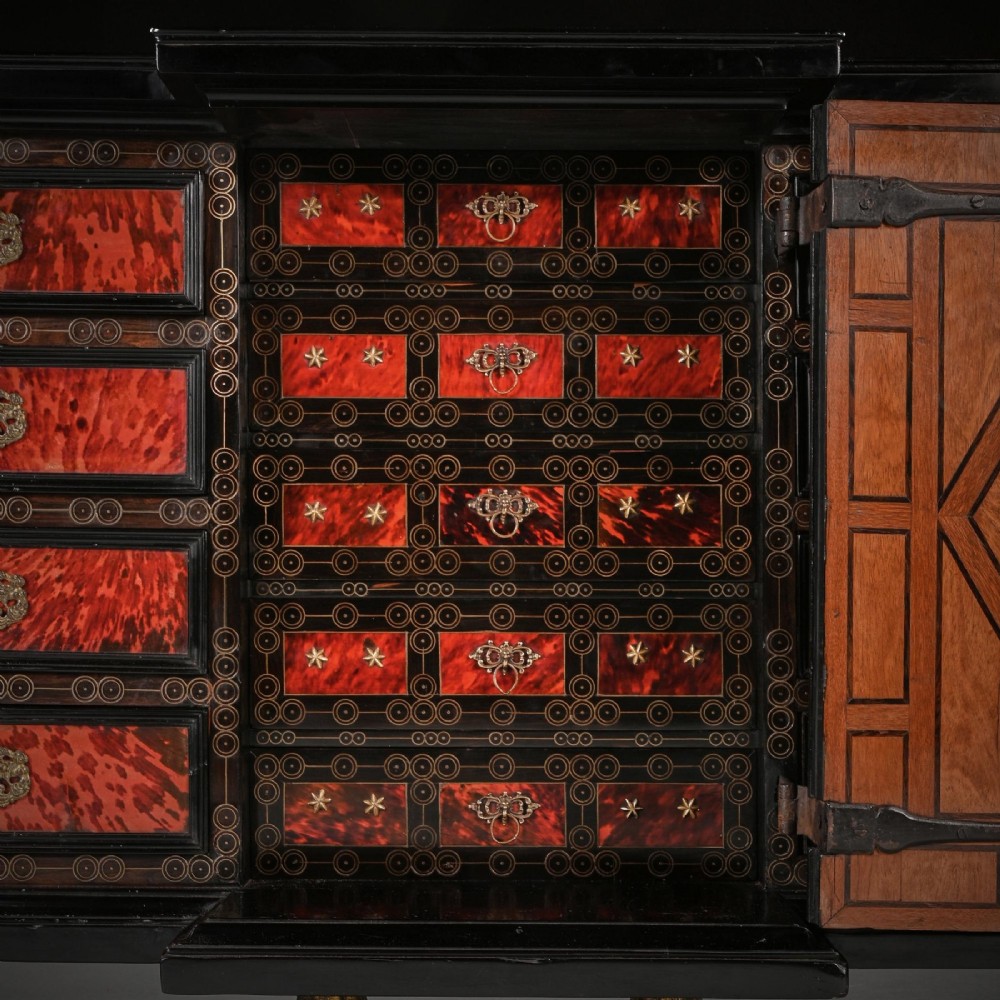 A pair of seventeenth-century Spanish Baroque ebonised and tortoiseshell cabinets featuring architectural central doors and gilt bronze mounts, elevated on tall metal stands. View XI