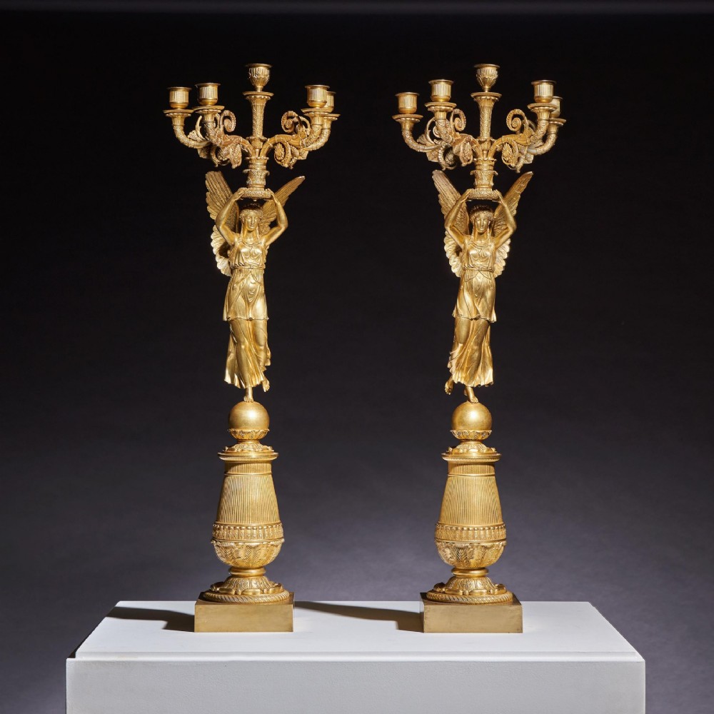 A pair of French Empire gilt bronze candelabra featuring winged Victory figures supporting multi-arm candle holders on pedestals. View II