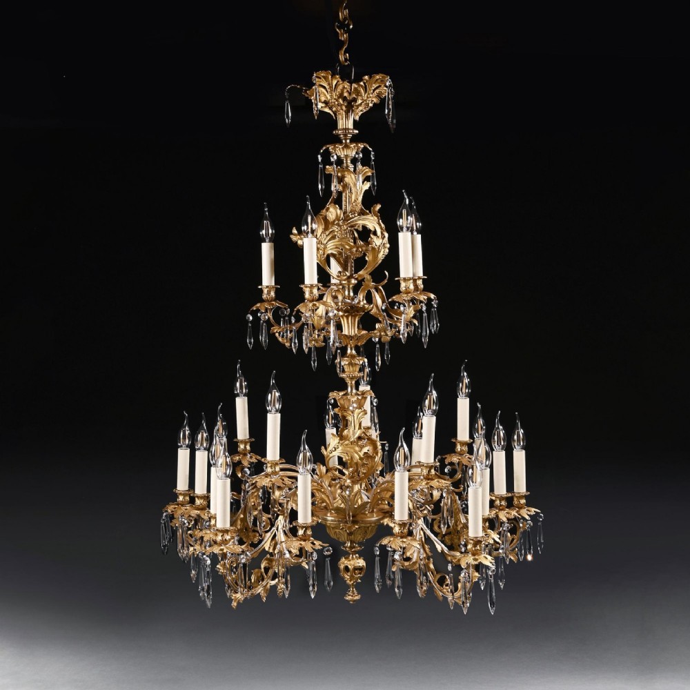 A late nineteenth-century Louis XV style gilt bronze chandelier with twenty-five candle lights across two tiers, embellished with cut glass droplets and ornate scrolling metalwork. View II