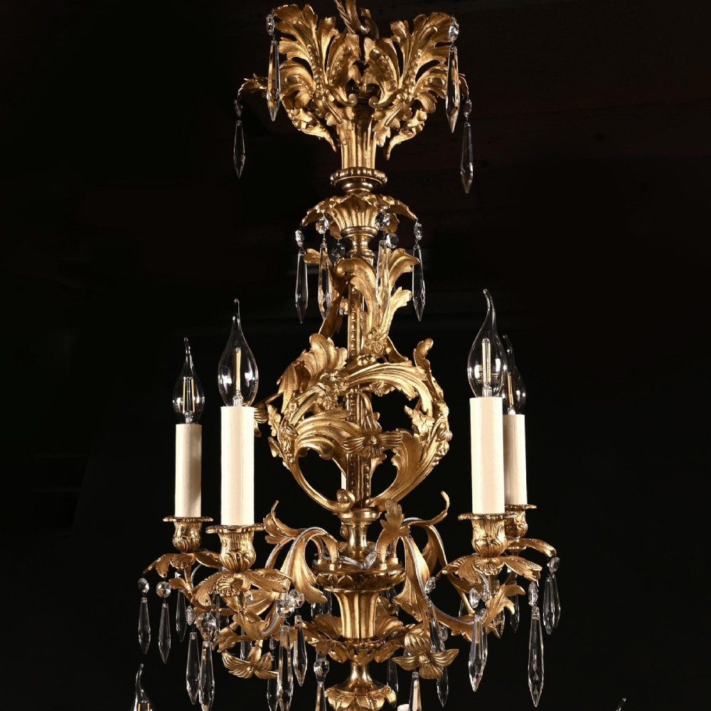 A late nineteenth-century Louis XV style gilt bronze chandelier with twenty-five candle lights across two tiers, embellished with cut glass droplets and ornate scrolling metalwork. View III