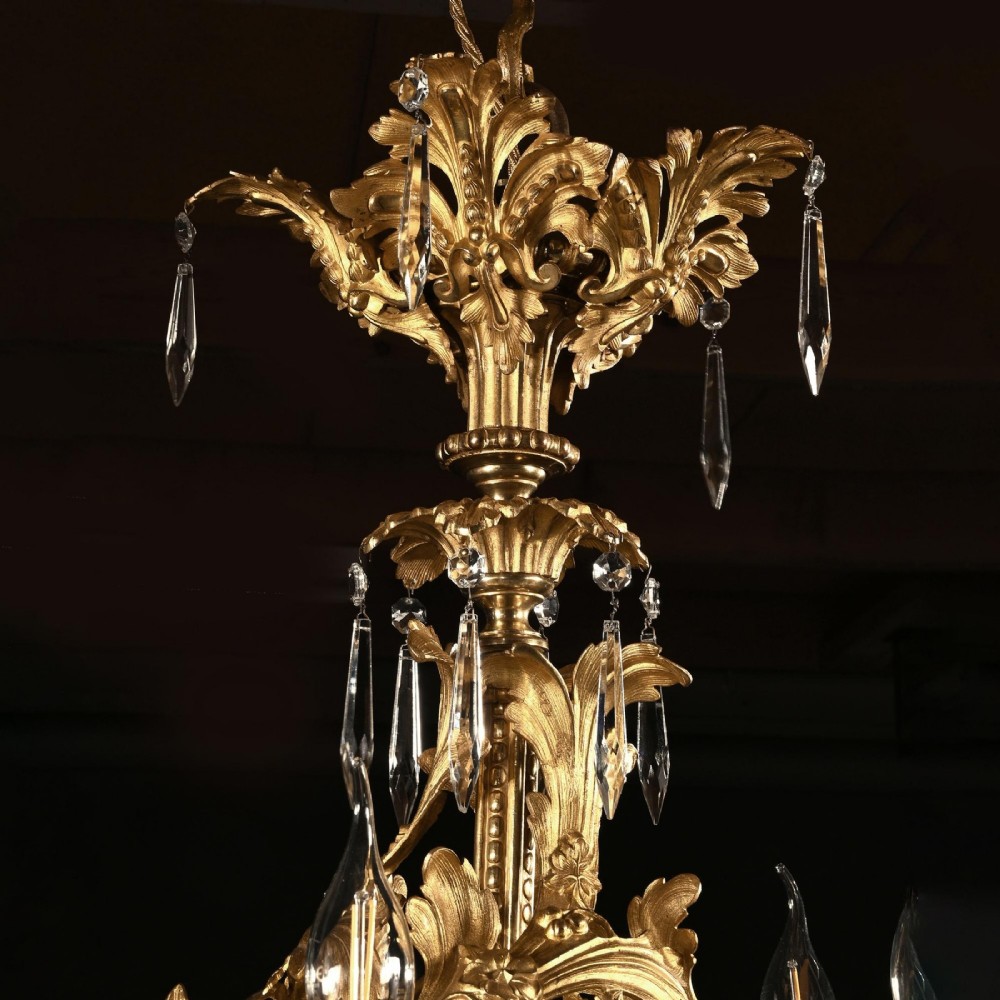 A late nineteenth-century Louis XV style gilt bronze chandelier with twenty-five candle lights across two tiers, embellished with cut glass droplets and ornate scrolling metalwork. View IV