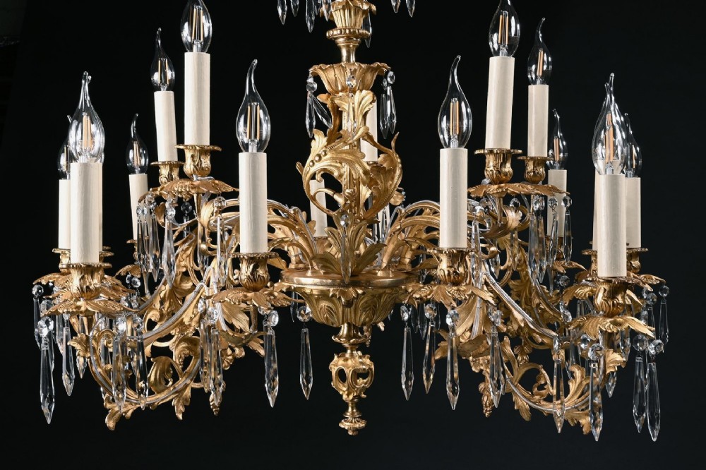 A late nineteenth-century Louis XV style gilt bronze chandelier with twenty-five candle lights across two tiers, embellished with cut glass droplets and ornate scrolling metalwork. View VI