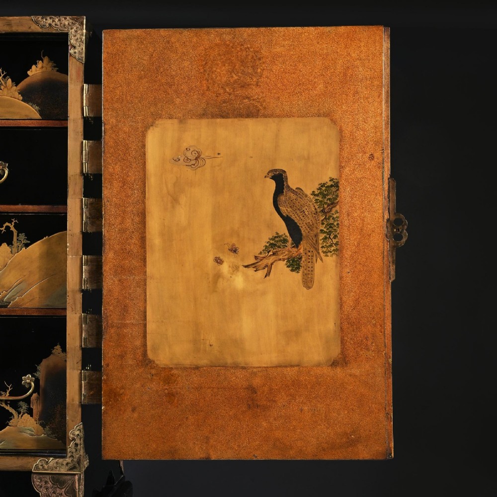A black lacquered Japanese cabinet decorated with gold maki-e landscape scenes, featuring ornate brass mounts and elevated on a simple black stand. View XI