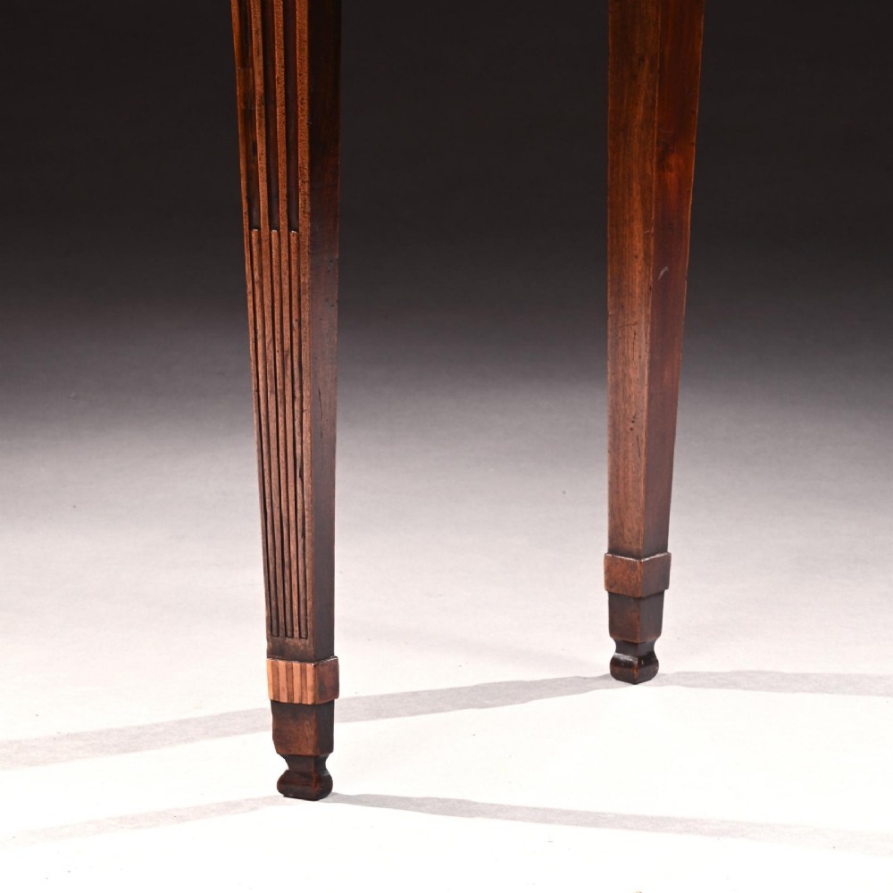 A George III mahogany tea table featuring a serpentine fold-over top, fluted tapered legs, and flame mahogany veneers on the frieze. View VI