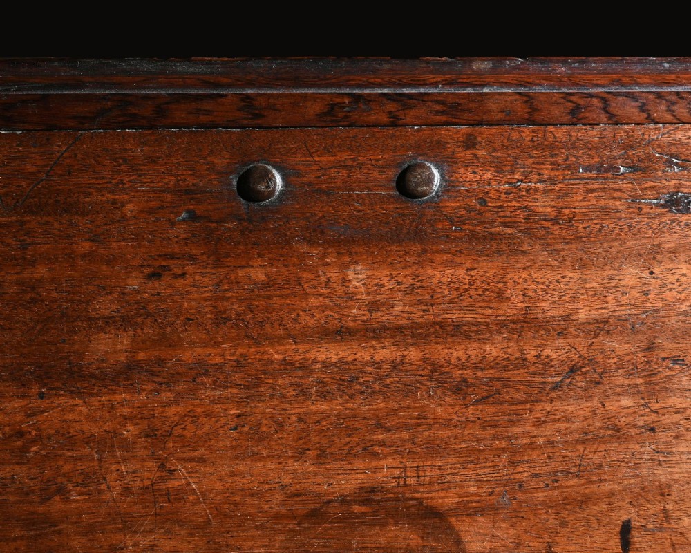 A dark mahogany Portuguese colonial chest featuring three raised diamond-moulded panels with central pierced brass mounts above a row of lower drawers. View V