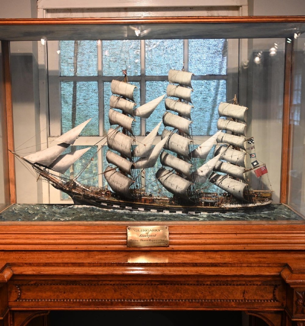 A detailed scale model of a three-masted tea clipper ship in full sail set within a seascaped display inside a glazed oak wood case with a brass plaque. View VI